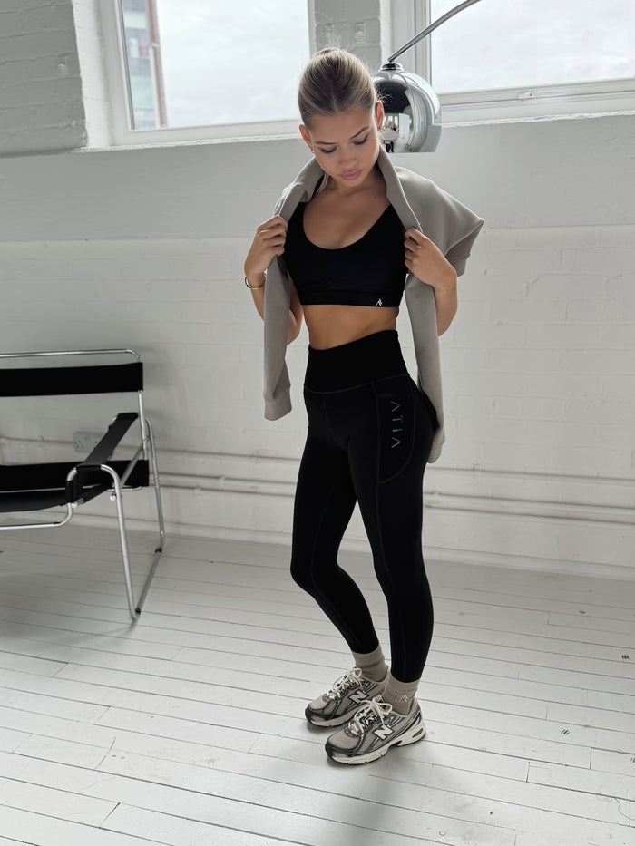 Black Intention Leggings with high waist and mesh detail, worn with grey cardigan in gym setting