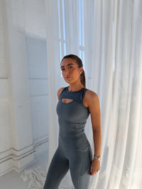 Raise Built-in-Bra Vest in Turbulence grey, worn by model, featuring peephole cutout detail and cropped fit.