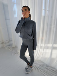 AERO TRACK JACKET in TURBULENCE, charcoal grey full-zip jacket with high neck worn by woman with matching leggings