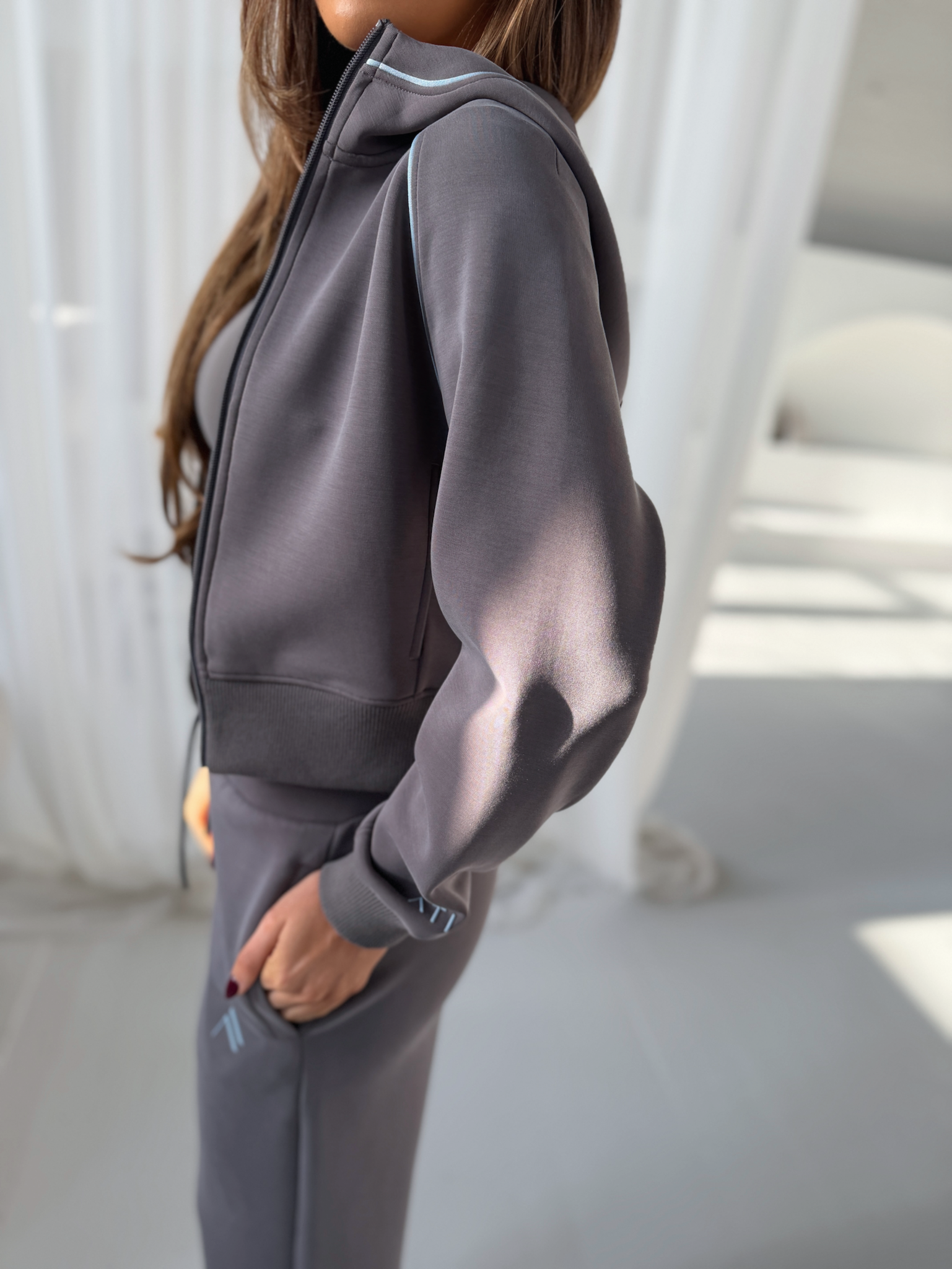 VELA Hood Jacket in Truffle, worn side view showing cropped zip-up design with banded cuffs and hem