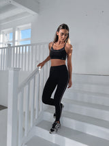 Woman in black athletic wear standing on a white staircase