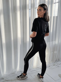 DIRECTION LEGGINGS BLACK, high-waisted full-length leggings worn by model with back view against sheer white curtains