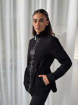 Model wearing black Prevail Jacket from Atia Active against white voile curtains