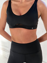 FORTIFY Sports Bra in Black, worn by model showing scoop neckline, supportive cup structure, and removable cups detail.