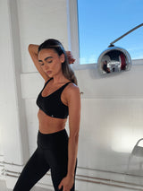 FORTIFY Sports Bra in BLACK, worn on model in side profile pose with white brick wall background